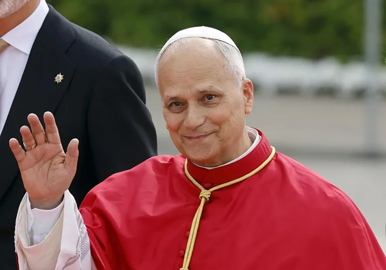 La visita de León XIV un reto para la seguridad Cardenal sonriente con hábito rojo, saludando con la mano en un entorno exterior.